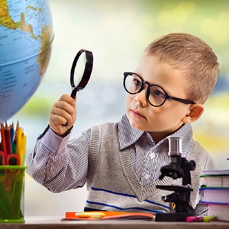 Boy looking through magnifying glass at globe