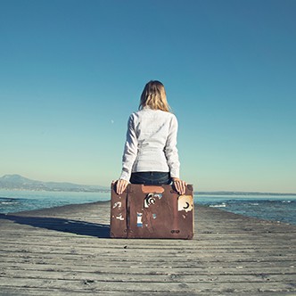 woman sitting on her suitcase waiting for the sunset