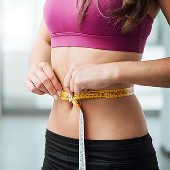 Slim woman measuring her thin waist