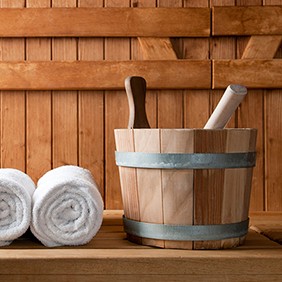 Wooden bucket and white rolled towels in a sauna