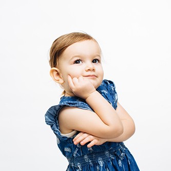 Small girl with arms crossed looking up,  isolated on white studio background