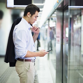 Businessman looking at his phone and waiting for subway