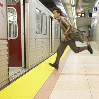 Young man running to subway train, side view