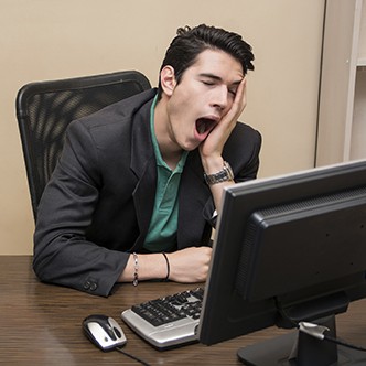 Tired bored young businessman sitting in office yawning